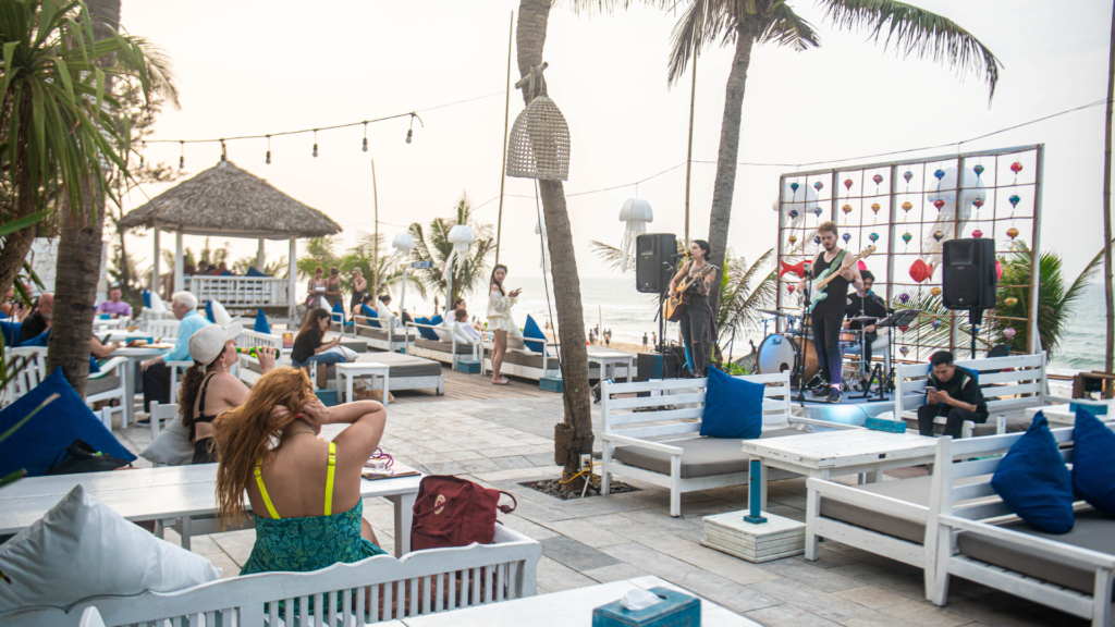 Guests enjoying live music on beachfront loungers at Shore Club, An Bang Beach in Hoi An, Vietnam.