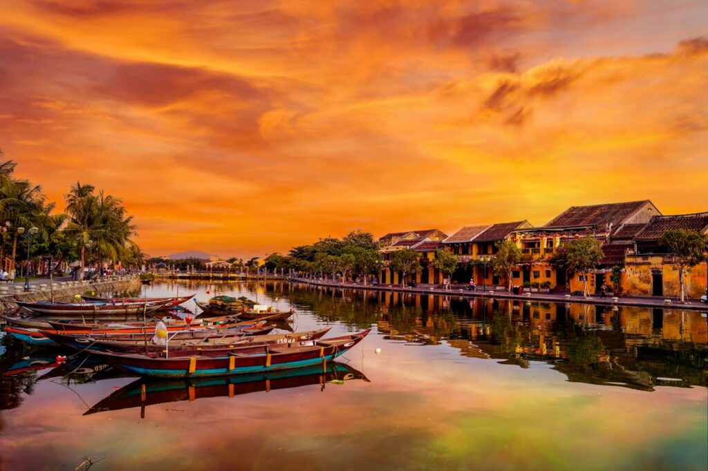 Sunset over Hoi An's Old Town with colorful lanterns illuminating the charming streets and the peaceful reflection on the Thu Bon River.